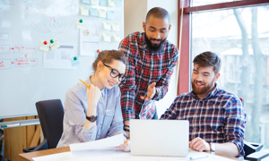 Glada kollegor vid skrivbord, två män och en kvinna