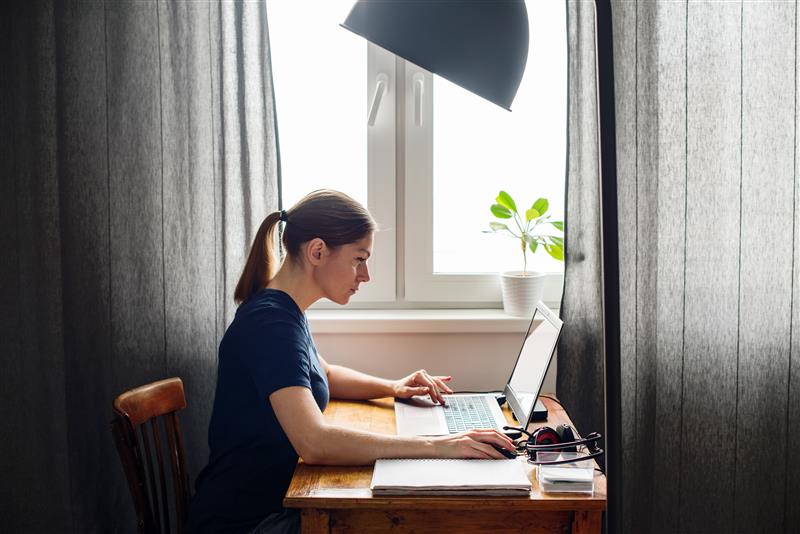 Person vid bord vänd mot laptop